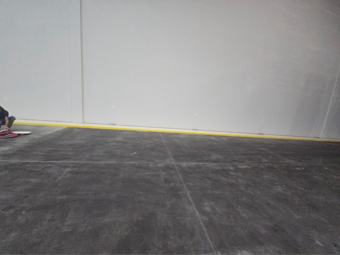 Warehouse floor treatment in progress, with the finished section showing a wet-look gloss