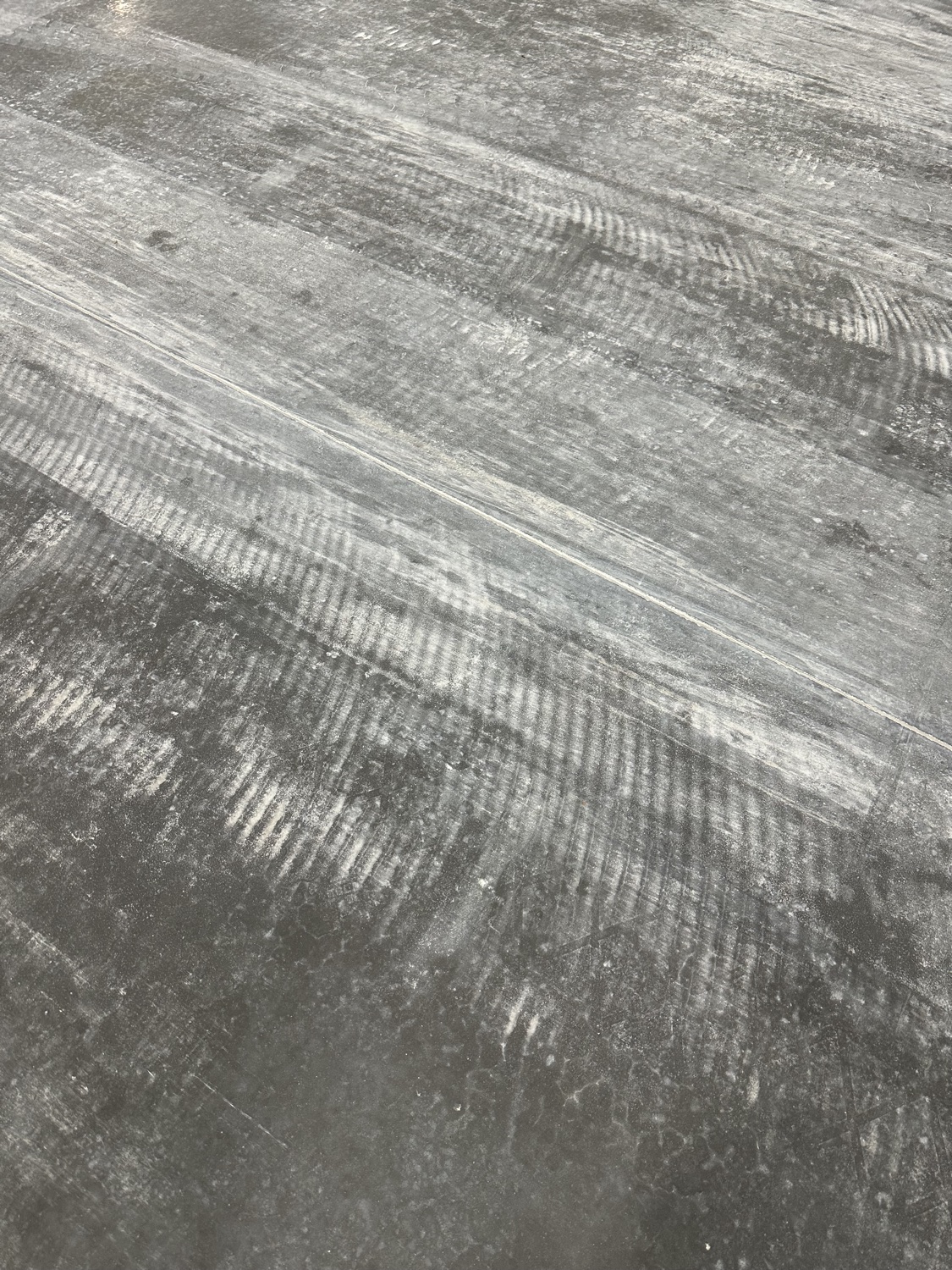 Large polished warehouse floor mid-project, ladder and columns reflected in the finished section