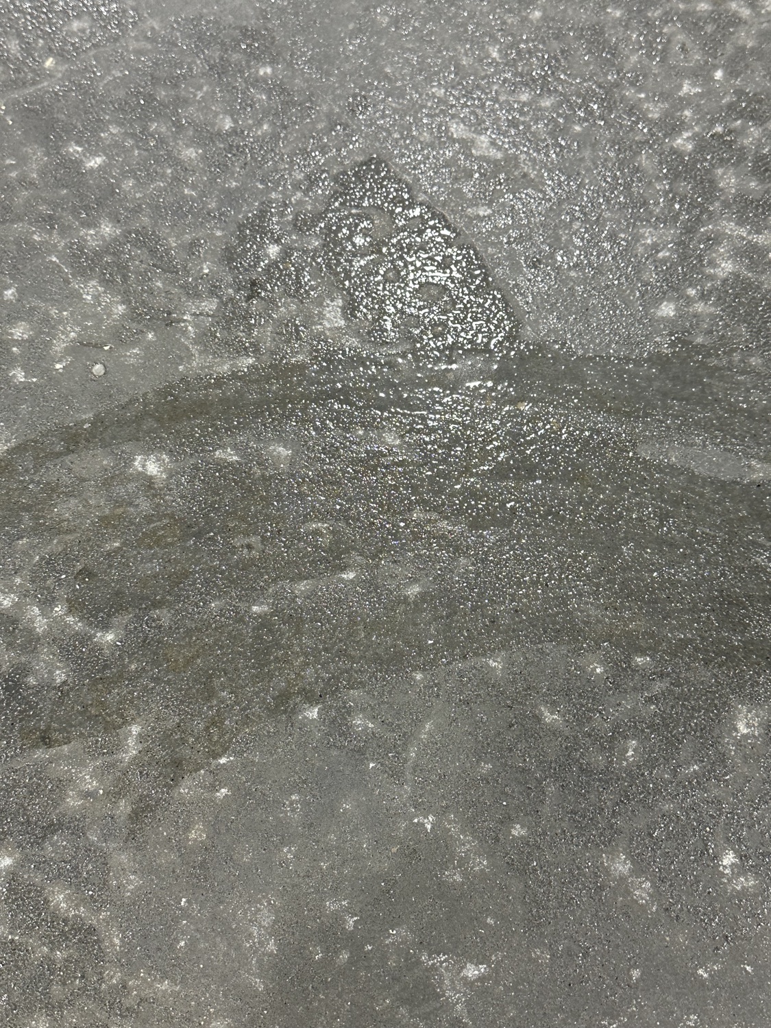 Dark moisture patch with white efflorescence blooming across a warehouse floor