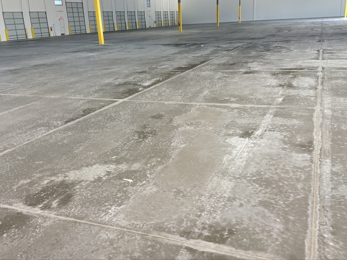 Moisture cure whitening a warehouse slab bay by bay in front of a row of dock doors