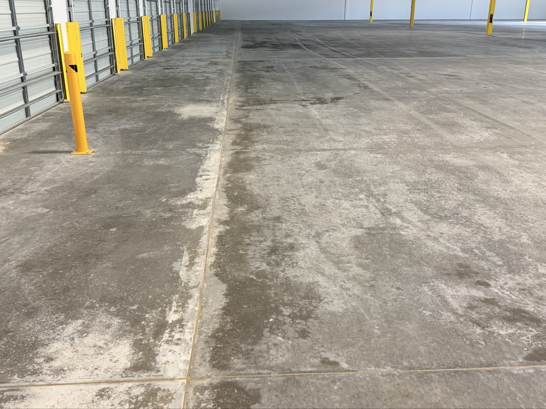 Moisture darkening a warehouse slab along a row of dock doors